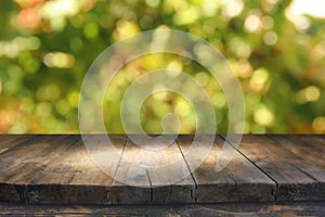 Empty rustic table in front of green spring abstract bokeh background. product display and picnic concept. photo