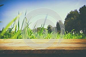 Empty rustic table in front of low angle view of fresh grass. product display and picnic concept.