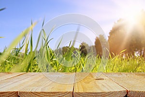 Empty rustic table in front of low angle view of fresh grass. product display and picnic concept.