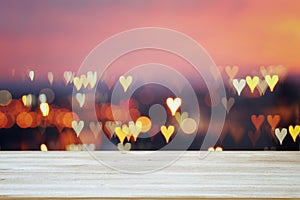 Empty rustic table in front of Valentine& x27;s day romantic glitter bokeh background with many hearts lights
