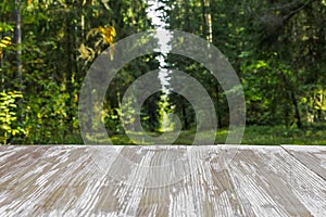 Empty rustic wood table top on blurred forest background at summer. Can montage or display your products