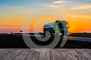 Empty rustic wood table top with motion blurred truck at sunset