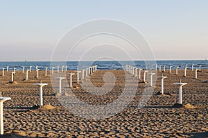 Empty sand beach of Grado, Italy Empty parasol stands waiting for summer with clear blue sky at the background.