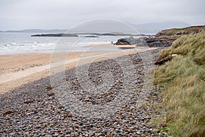 Empty sandy beach at low tide and blue water of Atlantic ocean. West coast of Ireland. Cloudy low sky. Irish nature landscape