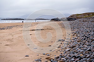 Empty sandy beach at low tide and blue water of Atlantic ocean. West coast of Ireland. Cloudy low sky. Irish nature landscape