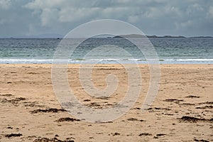 Empty sandy beach at low tide and blue water of Atlantic ocean. West coast of Ireland. Cloudy sky. Irish nature landscape