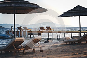 Empty sandy beach with sunbeds and umbrellas on the seashore, summer vacation concept