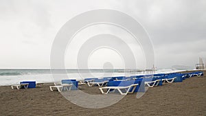 Empty sandy beach with sunbeds at windy stormy day. Dramatic stormy sea with huge waves. Empty coastline at winter. Travel destina