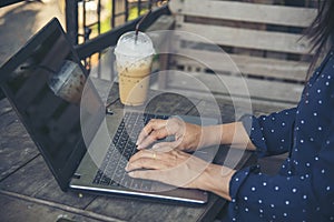 Empty Screen laptop Blogger Woman hands typing computer keyboard. Close up women hands using laptop sitting at coffee shop garden