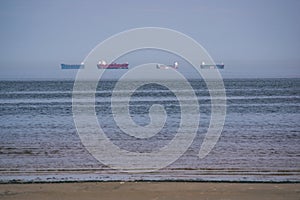 empty sea beach in spring with some birds and cargo ships on the