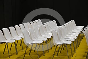 Empty seats in rows audience room white chairs yellow floor