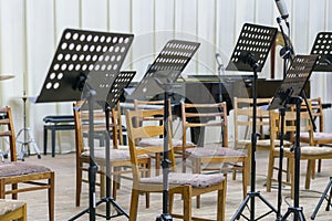 Empty seats and some instruments in music hall awaiting orchestra to come on the stage. black music stand on stage