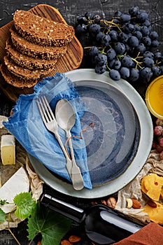 Empty serving blue plate with fork spoon in frame of food ingredients gastronomy appetizer snacks grapes cheese wine