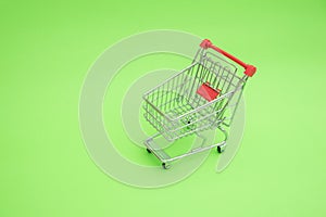 Empty shooping trolley cart on green background photo