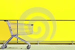 Empty Shopping Cart parked in front of large supermarket. Consumerism concept