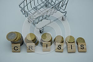 An empty shopping cart next to coins with the words crisis