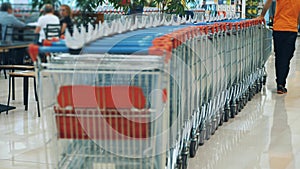 empty shopping cart. supermarket or shopping center, mall. A supermarket employee or worker, wearing an orange vest
