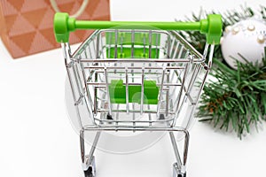 Empty shopping cart, trolley on white background with craft paper shopping bag and green decorated fir tree branches