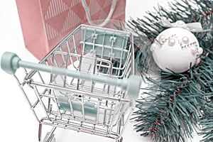 Empty shopping cart, trolley on white background with craft paper shopping bag and green decorated fir tree branches