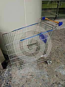 The empty shopping trolley is blue and made of iron