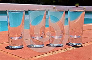 Empty shot glasses next to swimming pool detail