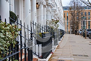 Empty sidewalk and row of beautiful white Edwardian houses in Kensington