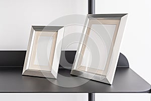 Empty silver small portrait frames, blank canvas, picture mock up, living room shelf