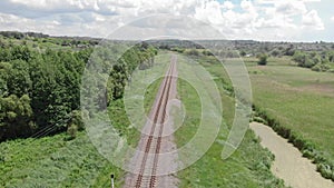 Empty single railroad in countryside. Drone flying over railway surrounded by forest and field. Cargo delivery. Transportation