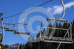 empty ski lift against the background of blue sky and fir trees.