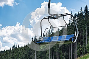 Empty ski lift on a background of forest and blue sky. Holidays in mountains in summer. Ecotourism