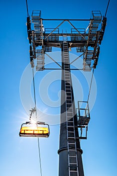 Empty ski-lift chair and cable car mast