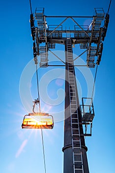 Empty ski-lift chair and cable car mast