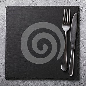 Empty slate stand and cutlery on the table. Food background