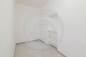 Empty small room with white walls and built-in niche for shelves in an old flat before renovation.