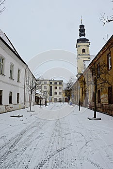 Prázdna zasnežená františkánska ulica s barokovou vežou kostola svätého Jakuba v pozadí. Lokalita Trnava, západné Slovensko.