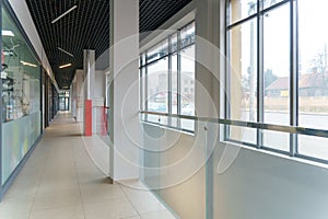 An empty space with railings and large windows. The modern interior of the lobby of the office building. A lighted long corridor