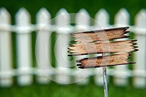 An empty space on the sign for text and advertising in front of a white fence on a green lawn