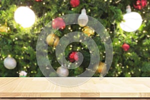 Empty space of wooden textured table top with blurry Christmas tree and New Year bokeh at winter night atmosphere for