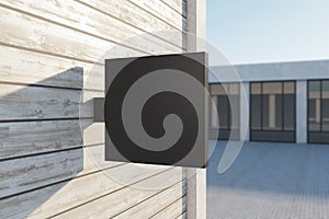 Empty square black stopper on wooden building. Bright city with sunlight background. Ad, pub, cafe, or restaurant banner. Mock up