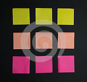 Empty square multi-colored stickers hang on a black board, business concept