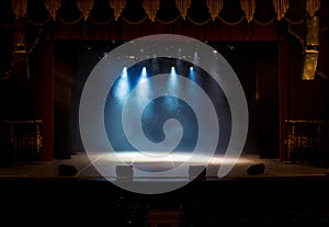 An empty stage of the theater, lit by spotlights and smoke