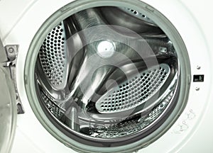 An empty stainless steel bubbled drum of white washing machine through opend door