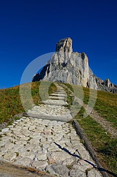 Empty stone trail leads up towards the towering mountaintop in the Dolomites.