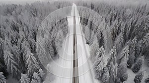 Empty straight asphalt road through winter snowy forest aerial view