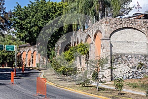 Empty street in city with orange metal fences, green directional signs indicating direction photo