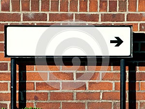 Empty street direction sign against a brick wall