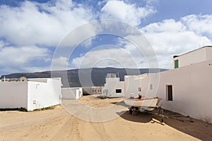 Empty street with sand and white houses in Caleta de Sebo on the island La Graciosa