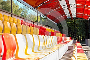 Empty street seats of hippodrome in red and yellow on the podium under a canopy to watch sporting
