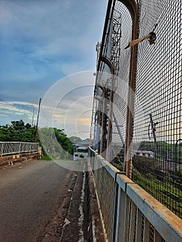 an empty street was bridged with an iron fence on its side