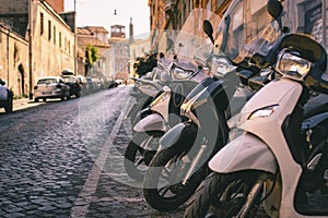 Empty streets of Rome, parked scooters and cars.